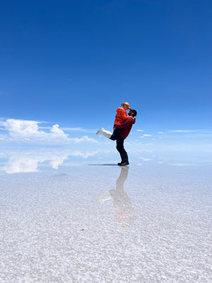 Digital nomads travelling through the Salt Flats in Bolivia near Uyuni. Couple travel, slow travel, working remotely, vegan travel, budget travel. Posing on the Salt Flats.