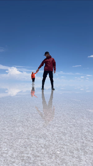 Digital nomads travelling through the Salt Flats in Bolivia near Uyuni. Couple travel, slow travel, working remotely, vegan travel, budget travel. Posing on the Salt Flats.
