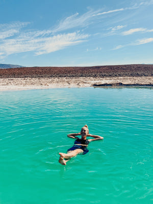 Digital nomads travelling through Atacama Desert, Chile in Salt Baths. Couple travel, slow travel, working remotely, vegan travel, budget travel. Laguna Baltinache near San Pedro de Atacama. Woman floating in salt water bath.