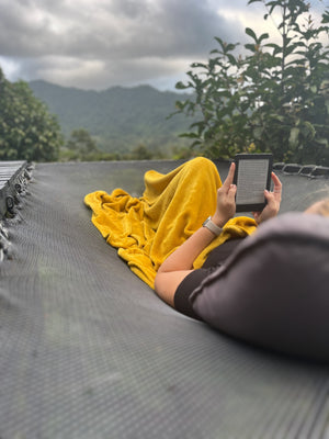 Digital nomads travelling in Costa Rica working remotely. Slow travel vegan travel and budget travel. Reading kindle in El Tigre overlooking forest.