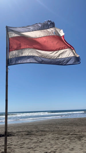 Digital nomads in Jaco Costa Rica on the beach with Costa Rica flag blowing in the wind.