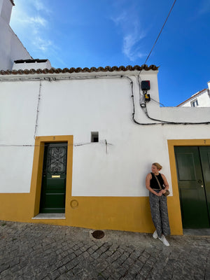 Yellow and white Portuguese house with green door with young woman standing out front.
