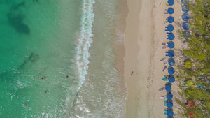 Digital nomads travelling the world.  Itinerary of Barbados based on couple travel, slow travel, working remotely, vegan travel, and budget travel. Overhead picture of the beach with umbrellas.