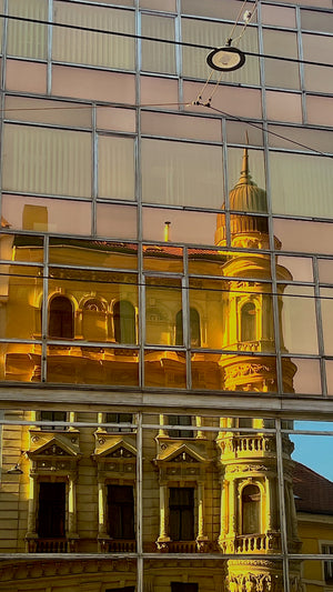 Digital nomads travelling through Prague. Couple travel, slow travel, working remotely, vegan travel, and budget travel. Prague architecture reflecting in a window of building. 